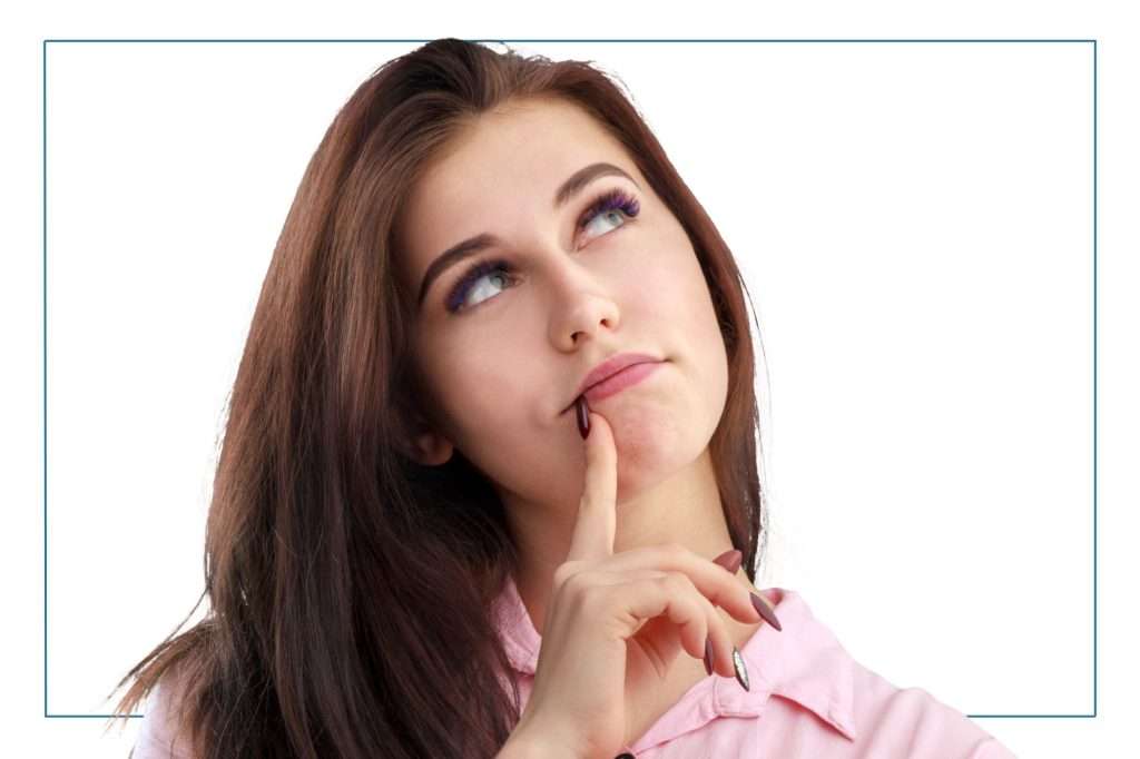 dark haired woman looking up to the right with her finger to her lips