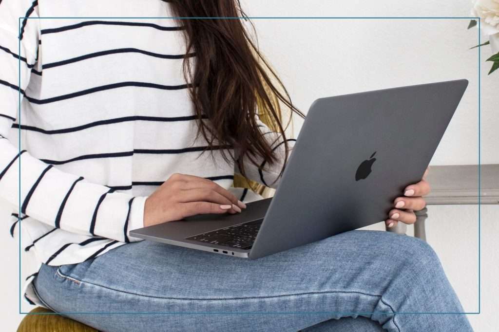 woman in striped shirt with laptop on her desk working on placing the meta descriptions on her website.