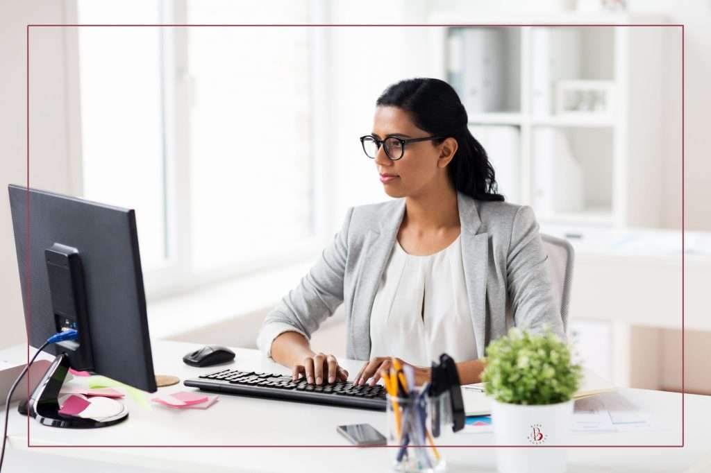 woman with glasses sitting at a computer doing a content audit on her website