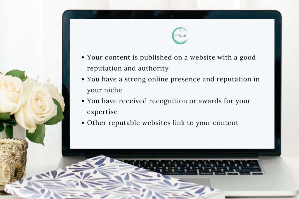 white roses in gold vase on a desk beside a blue and white notebook and a laptop with the text • Your content is published on a website with a good reputation and authority • You have a strong online presence and reputation in your niche • You have received recognition or awards for your expertise • Other reputable websites link to your content
