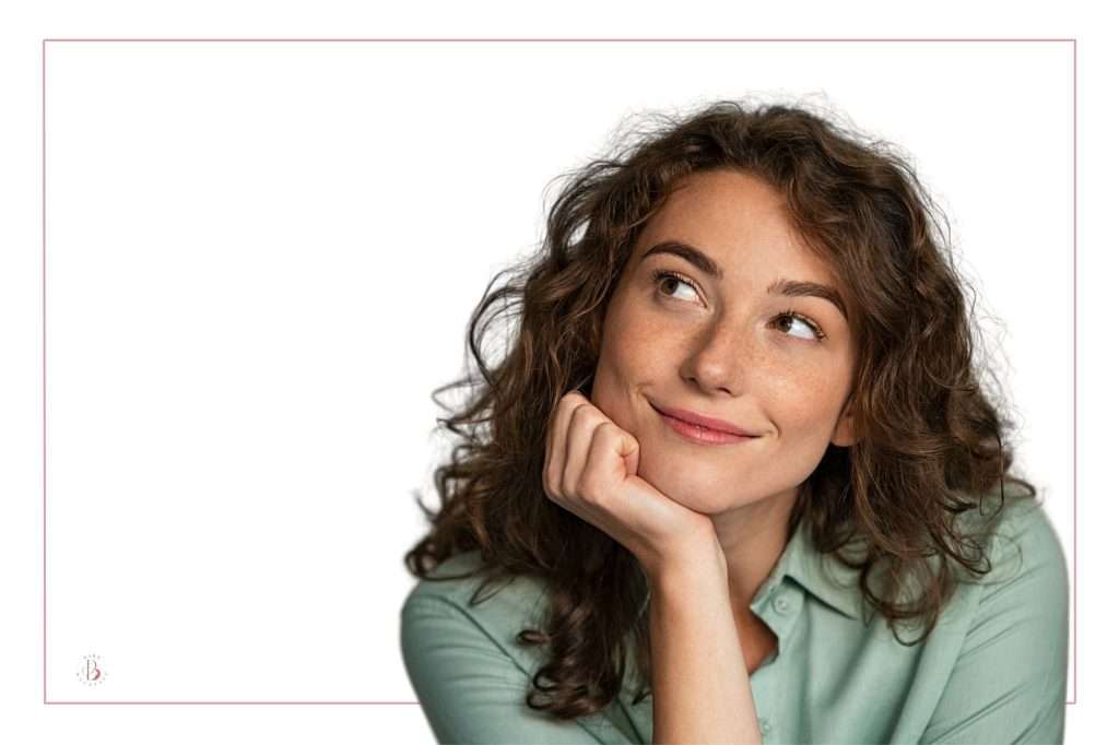 dark haired woman looking off to the left pondering