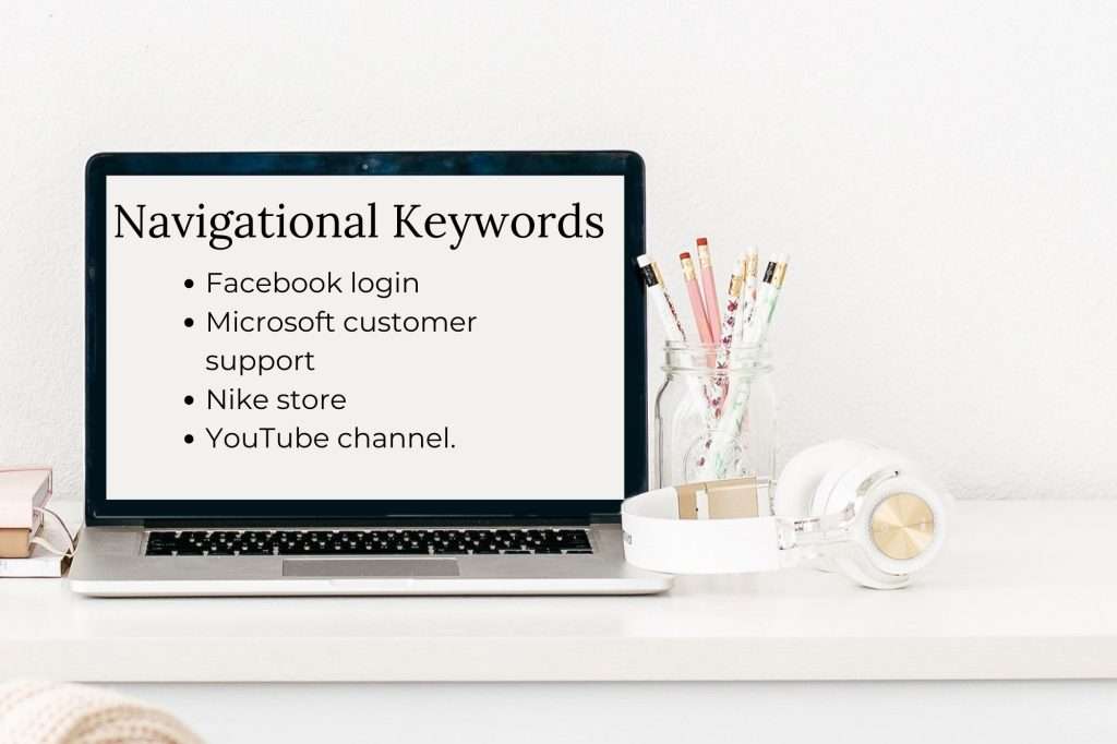 computer sitting on white desk with pencils to the left in a jar. White and rose gold headphones in front of the jar. On the white computer screen reads" Navigational keywords: Facebook login
Microsoft customer support
Nike store
YouTube channel. 