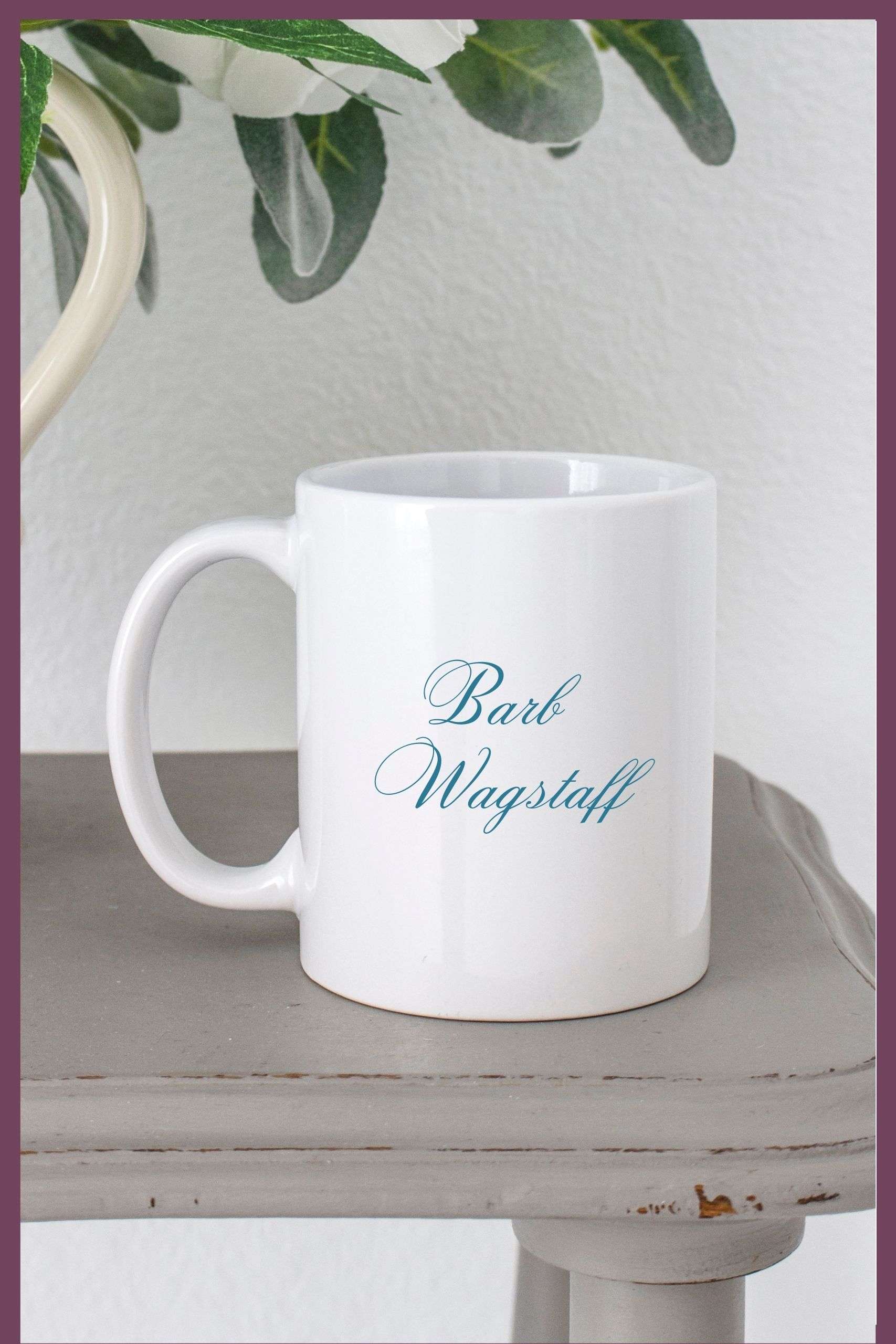 White much on a grey wooden table with the words Barb Wagstaff written in teal across the front of it.