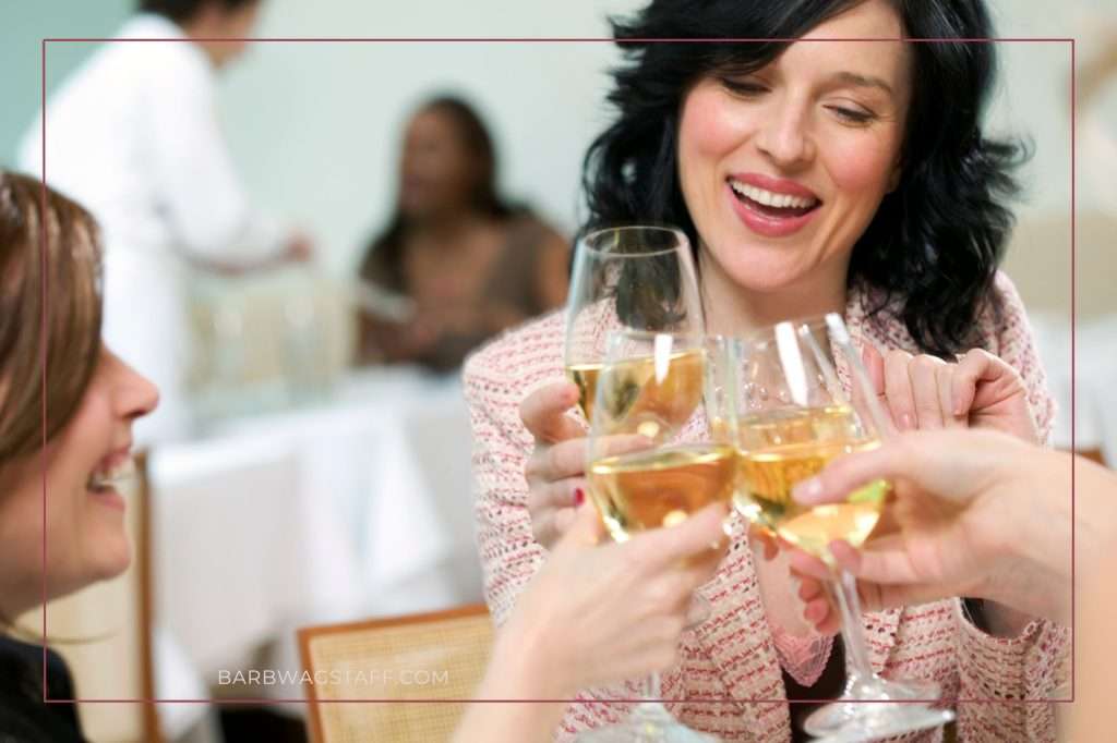 three women holding wine glasses, toasting their success.