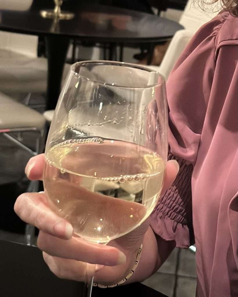 woman's hand holding a glass of white wine